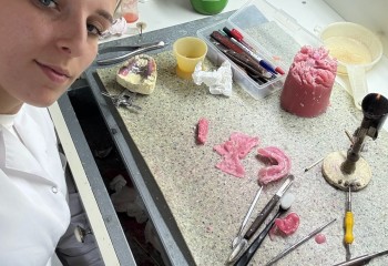 Zdjęcie przedstawia narzędzia niezbędne do wykonywania prac protetycznych oraz słuchacza szkoły prezentującego narzędzia